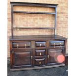 AN OAK DRESSER the upper section having open back and of two shelf configuration above a base of
