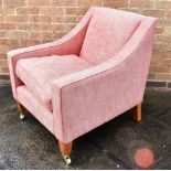 A 20TH CENTURY ARMCHAIR in pink upholstery and raised on square tapering legs on casters, H 84cm