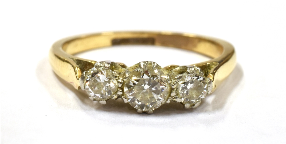 A DIAMOND TRIPLE STONE DRESS RING the three round cut diamonds set on a yellow gold shank with