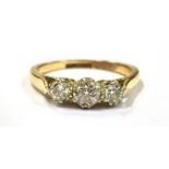 A DIAMOND TRIPLE STONE DRESS RING the three round cut diamonds set on a yellow gold shank with