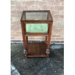 AN OAK PEDESTAL DISPLAY CABINET having a fall front door, raised on square supports with under