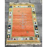 A CONTEMPORARY HANDWOVEN RUG with rust ground central field, the border decorated with stylised