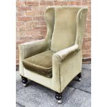 AN UPHOLSTERED GREEN WING ARMCHAIR raised on casters, H 102cm