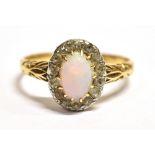 AN OPAL AND DIAMOND CLUSTER RING The opal measuring approx. 7mm x 5mm, surrounded by 14 8 cut