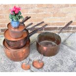 A COLLECTION OF VICTORIAN COPPER SAUCEPANS AND LIDS with iron handles, the largest 35cm diameter