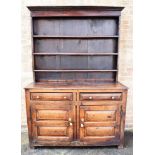 AN OAK DRESSER the upper section having a panelled back and a three shelf plate rack above a base, H