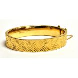 A VINTAGE 9CT GOLD ENGINE PATTERNED BANGLE The bangle fitted with a safety chin and push clasp,