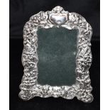 AN EMBOSSED SILVER STANDING PICTURE FRAME The frame 23cm by 14 cm, the silver embossed with