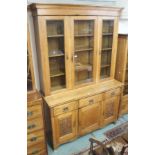 An oak Arts and Crafts bookcase with triple glazed doors over a base with three drawers over a