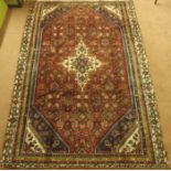 A red ground Sarouk rug with cream central medallion and blue and cream spandrels, 288cm x 186cm