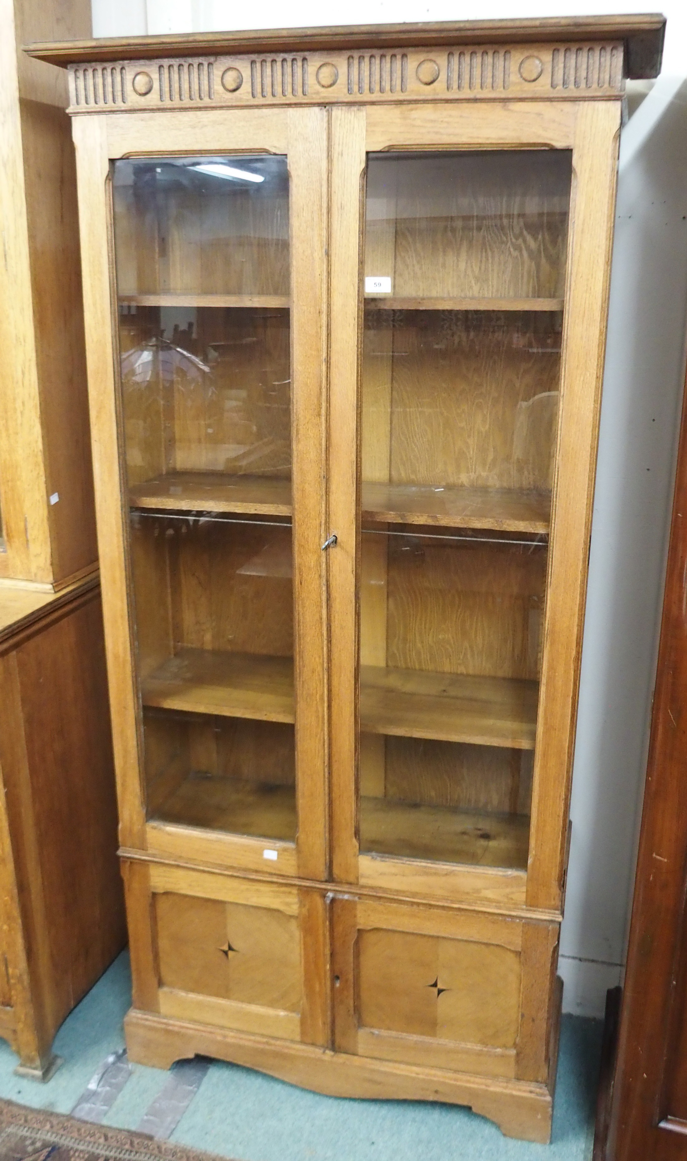 An oak bookcase with two glazed doors over doors with central inlay, 191cm high x 95cm wide x 34cm