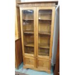 An oak bookcase with two glazed doors over doors with central inlay, 191cm high x 95cm wide x 34cm