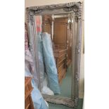 A large ornate wall mirror with bevelled glass, 173cm x 87cm Condition Report: Available upon