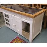 A white kitchen island with three drawers over a pair of doors and open shelves with granite style