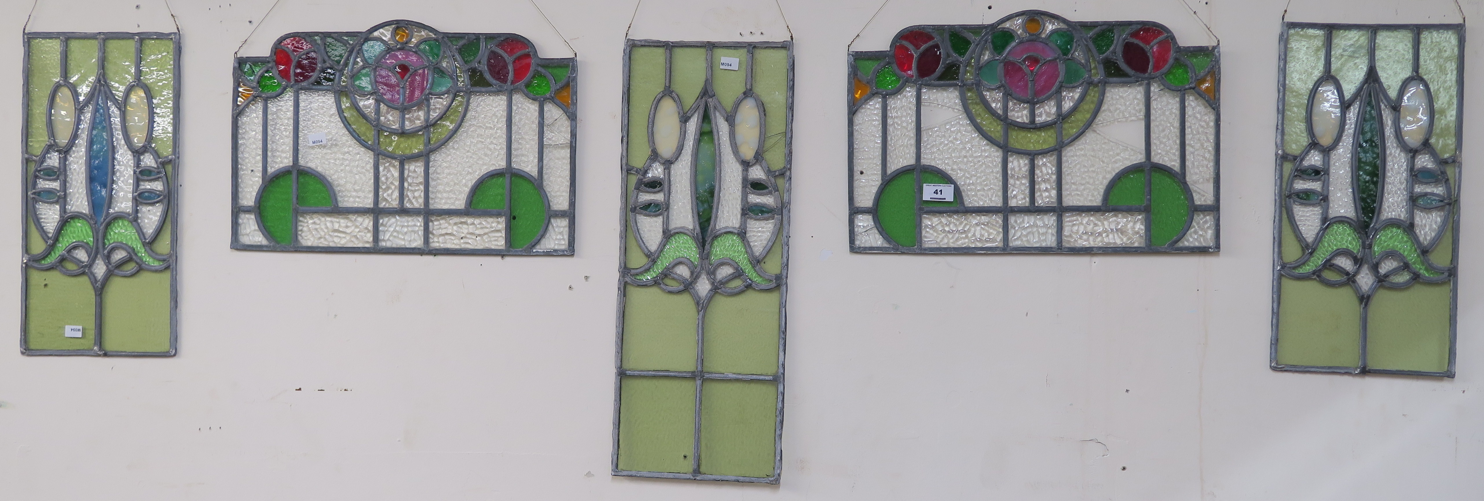 A leaded and stained glass panel, 56cm x 23cm with two matching panels, 43cm x 22cm and a pair of