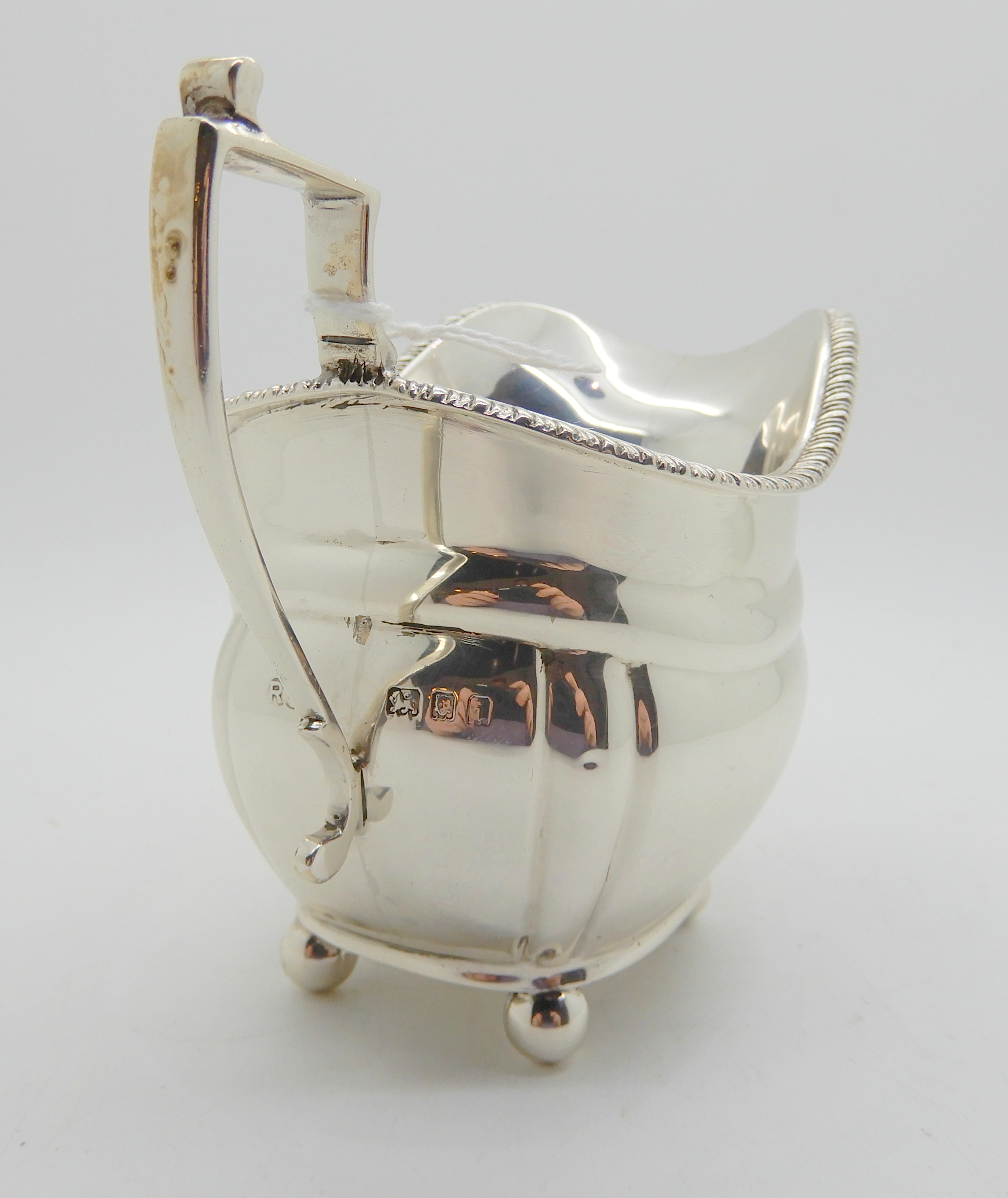 A silver cream jug, London 1924, of rounded rectangular form with lobed corners on four ball feet, - Image 3 of 5