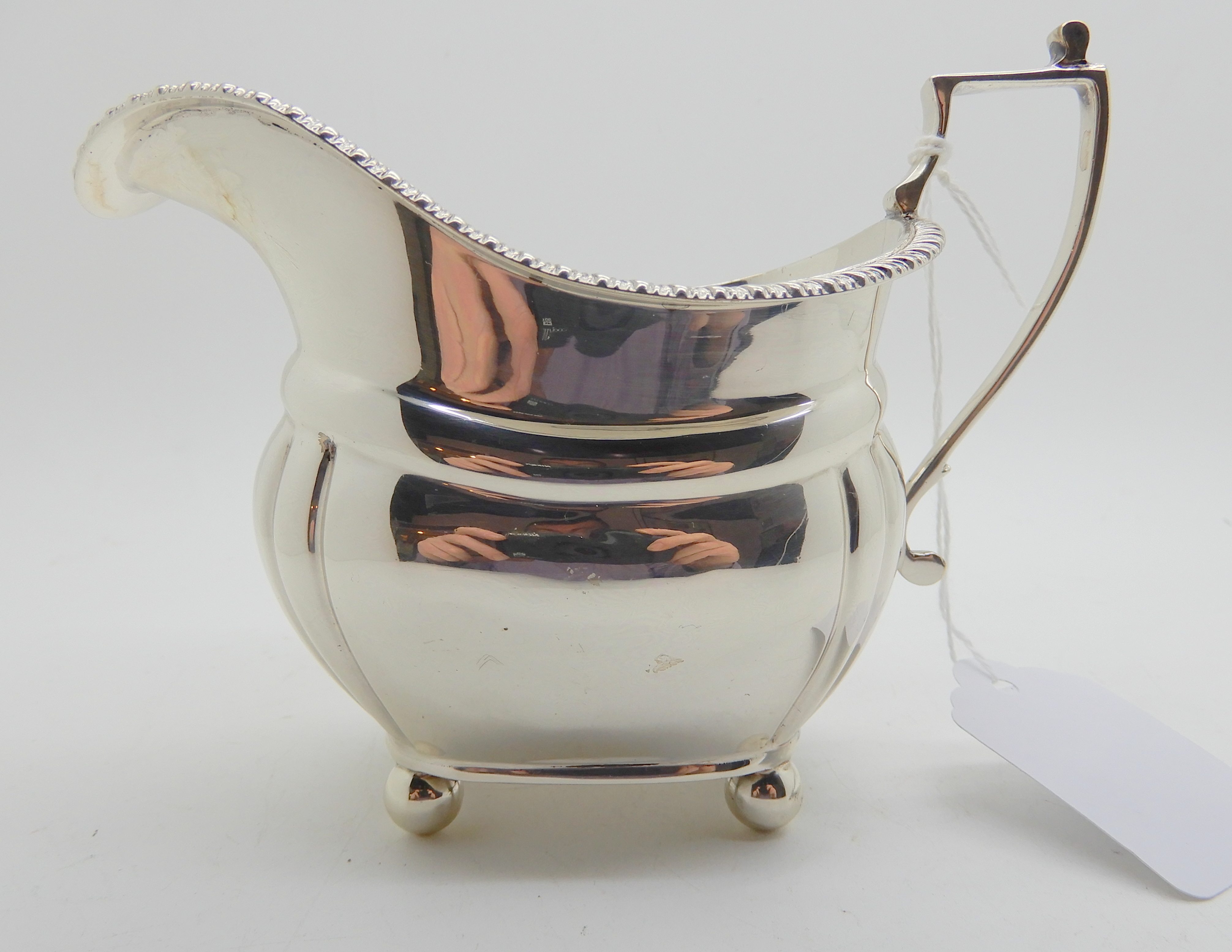 A silver cream jug, London 1924, of rounded rectangular form with lobed corners on four ball feet, - Image 2 of 5