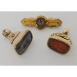 A yellow metal seal with a carved carnelian heraldic seal, a gold plated example and a 9ct brooch
