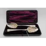 A cased pair of silver berry spoons, unclear London hallmarks, the stems with chased leafy