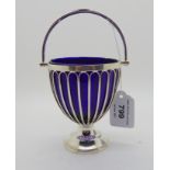 A silver sugar basket, Birmingham 1926, modelled as a planter with swing handle and blue glass liner