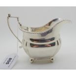 A silver cream jug, London 1924, of rounded rectangular form with lobed corners on four ball feet,