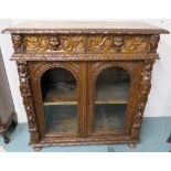 A Victorian carved oak cabinet with two drawers with mask handles over two glazed door, 105cm high x