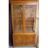 A yew wood display cabinet with two glazed doors over two cupboard doors, 196cm high x 107cm wide