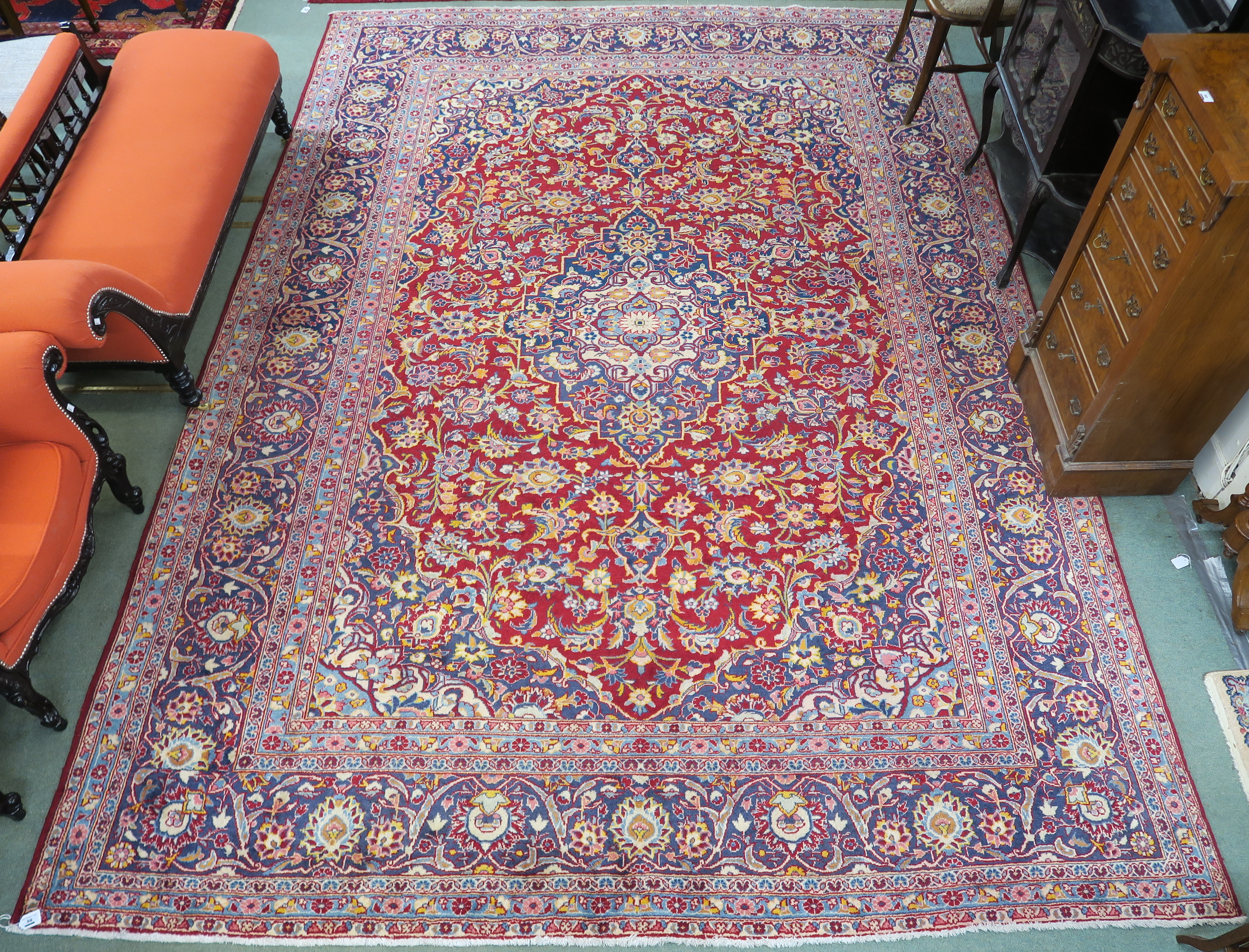 A large red ground Keshan rug with traditional design of blue central medallion, matching