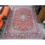 A large red ground Keshan rug with traditional design of blue central medallion, matching