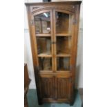 An oak corner cabinet with two glazed doors over cupboard doors, 167cm high x 70cm wide Condition