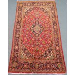 A red ground Fine Keshan rug with central medallion, matching spandrels and borders, 230cm x 130cm