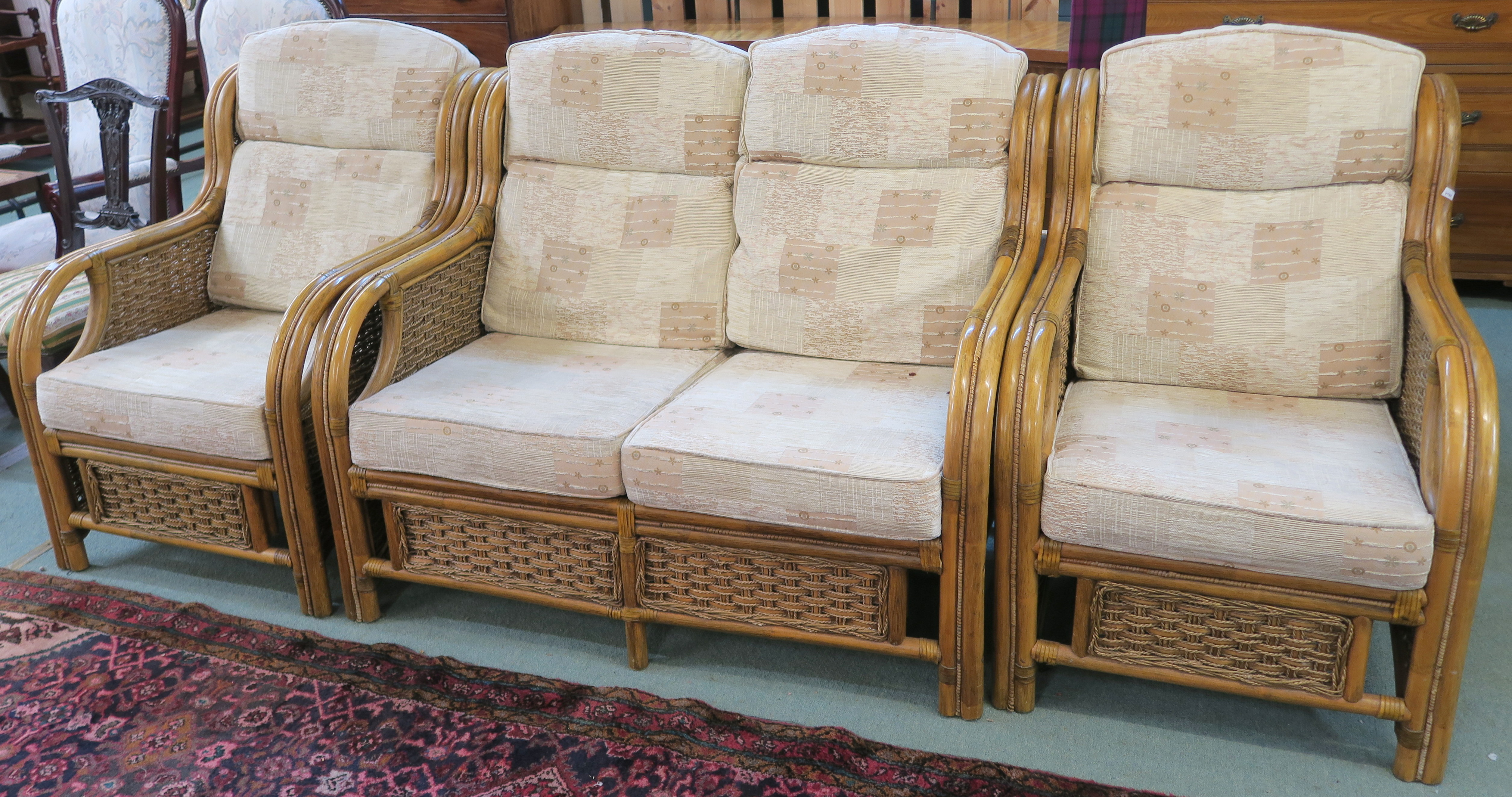 A cane three piece suite with two seater sofa and two chairs with a light fabric upholstery (3)