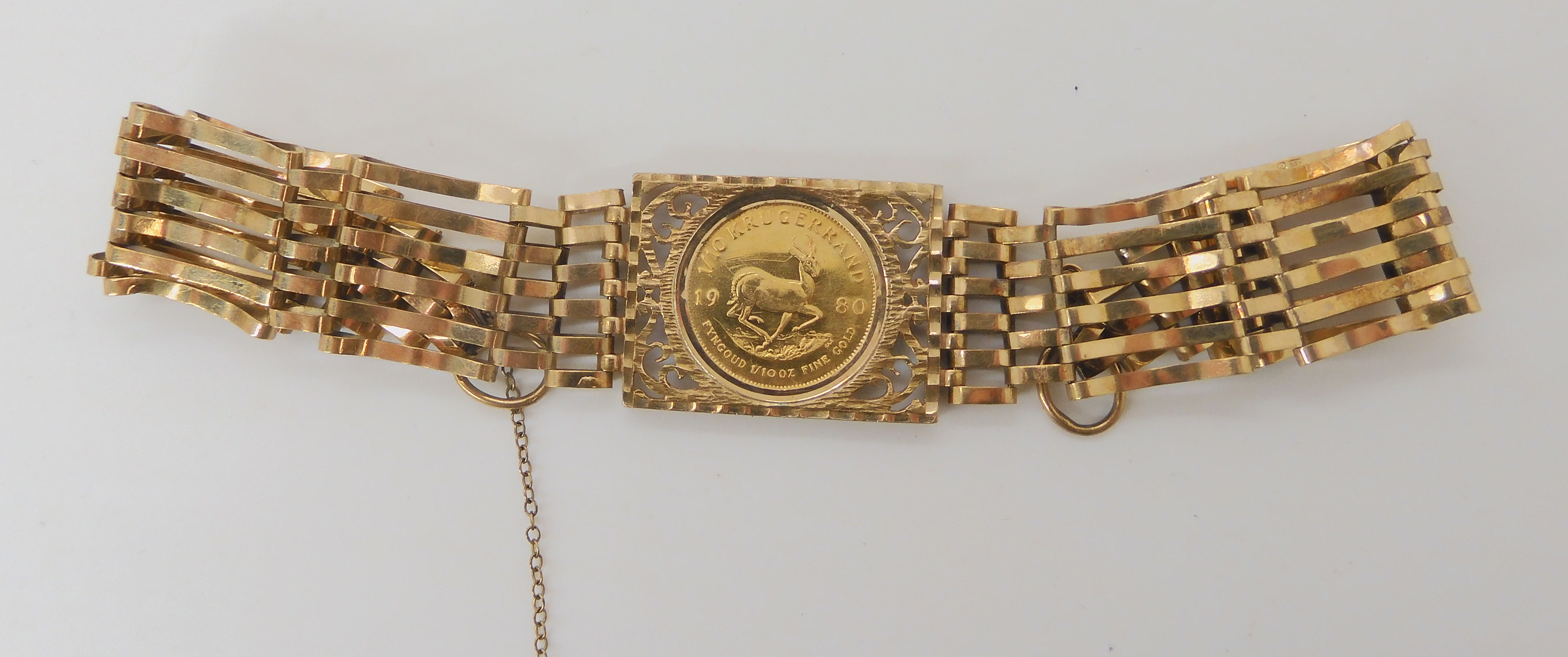 A 9ct gold gate bracelet set with a 1980 1/10th Krugerrand coin, weight combined 13.8gms there is no