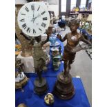 A spelter figure of a lady holding aloft a glass clock dial, together with another figure of a boy