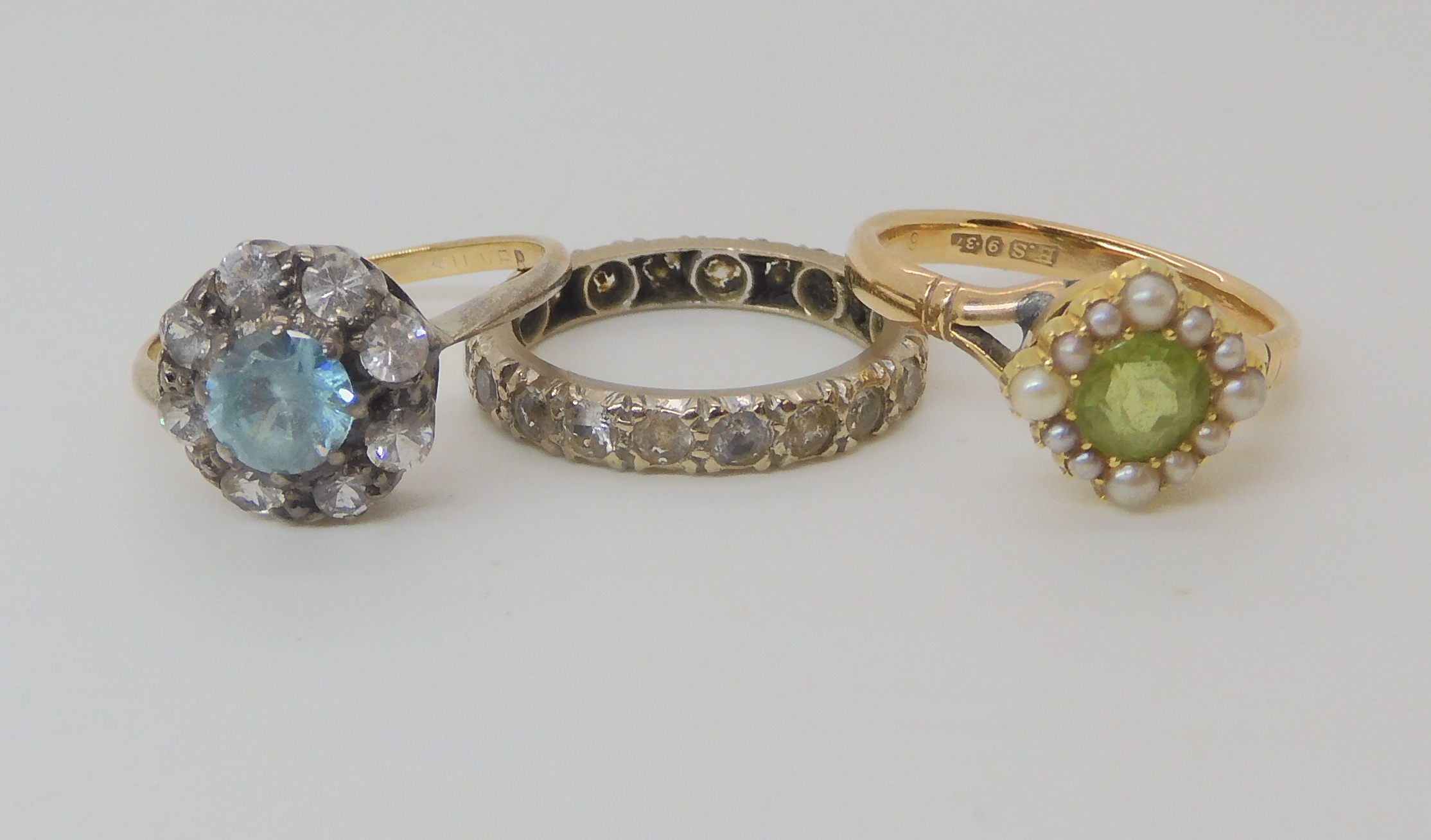 A 9ct gold peridot and pearl set ring size K1/2, a yellow metal clear gem set eternity ring size