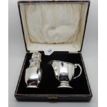 A cased silver sugar shaker with a silver cream jug, Birmingham 1935 and 1976, 302gms total