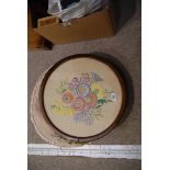 A circular embroidered panel, framed and glazed, 43cm wide and an embroidered cushion (2)