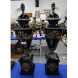 A pair of black glazed table lamps with rams head handles and swags of flowers Condition Report: