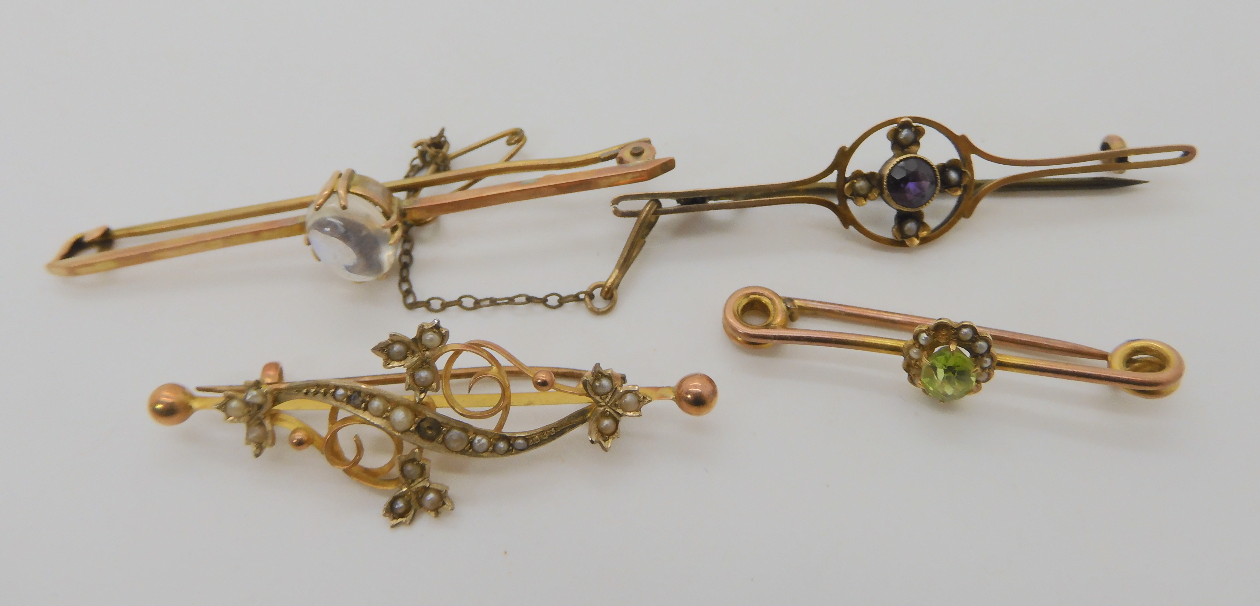 A 9ct moonstone bar brooch, a yellow metal peridot and pearl brooch and two further 9ct pearl set