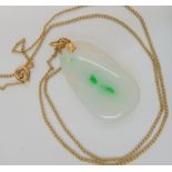 A white Chinese hardstone pendant carved with leaves with splashes of green, mounted in bright