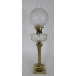 A BRASS COLUMN OIL LAMP with clear glass font and Duplex marked wheels, the shade with etched