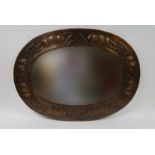 AN ARTS AND CRAFTS MIRROR of oval form, the brass frame with repousse decoration of fruit and
