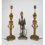 A PAIR OF GILDED METAL TABLE LAMPS with flame finals above a ribbon tied portrait and a tapering