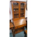 An oak bureau bookcase with two glazed doors over base with fitted interior and open shelves,