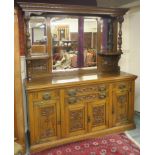 An oak mirrored back sideboard with carved supports over a base with four carved drawers over four