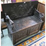 An oak carved monks bench, 101cm high x 107cm wide x 44cm deep Condition Report: Available upon