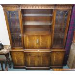 A reproduction mahogany breakfront cabinet with open shelves over drop front flanked by two glazed