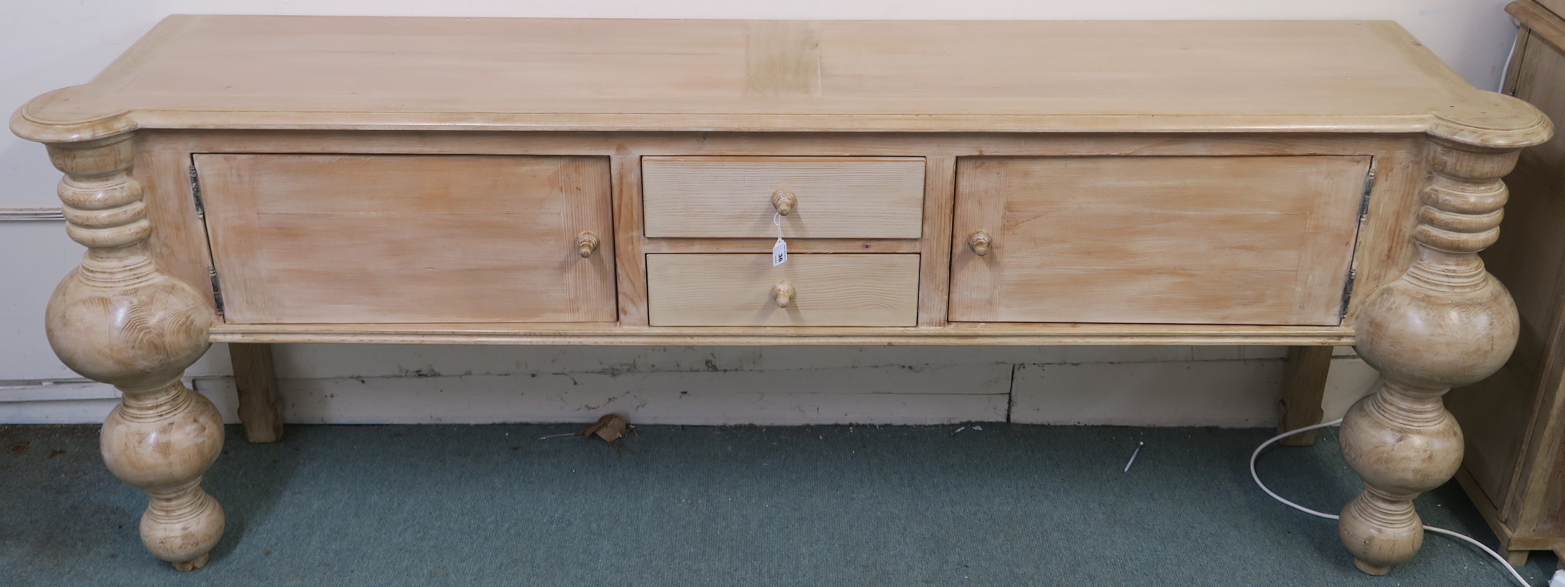 A modern limed pine console table with two drawers flanked by two doors with baluster shaped