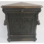 A Continental oak corner cabinet with single carved frieze drawer with mask handle over a carved
