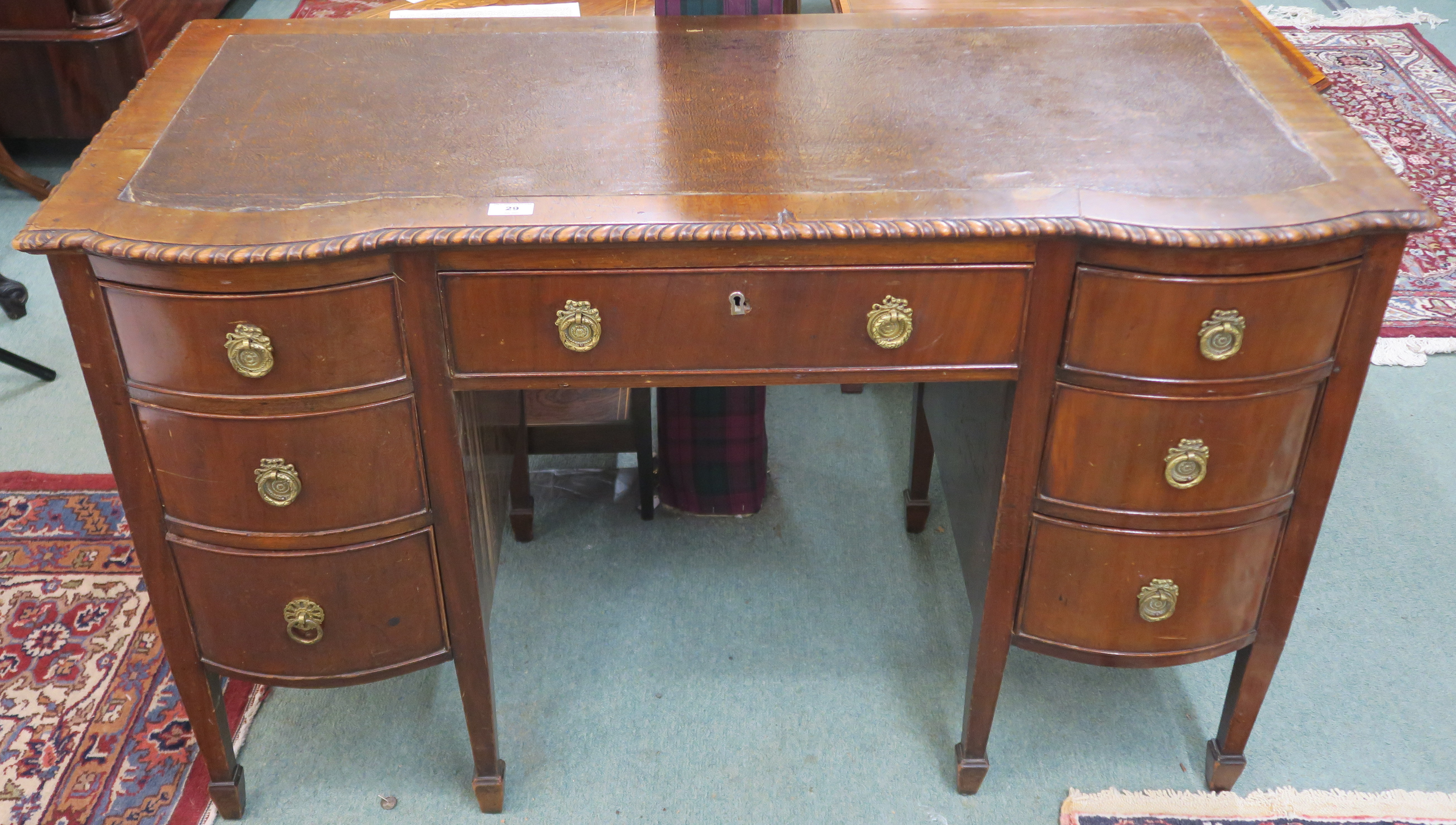 A mahogany writing desk with rexine skiver with central drawer flanked by six bow front drawers on